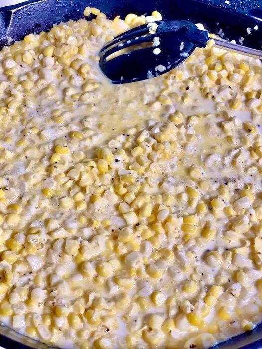 Old fashioned creamed corn cooking in a skillet, creamy and golden with bits of fresh corn.