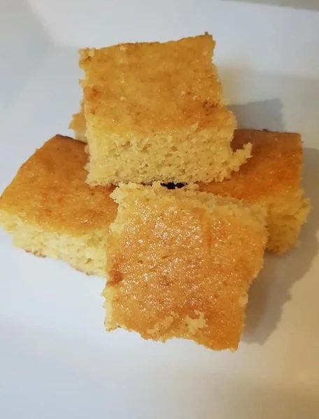 Moist sweet cornbread squares stacked on a white plate, golden brown top – sweet cornbread recipe