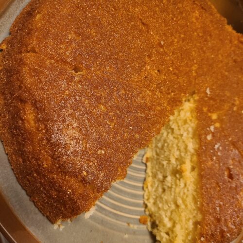 A sliced piece of aunt's mayonnaise cornbread on a plate, showing its soft texture inside.