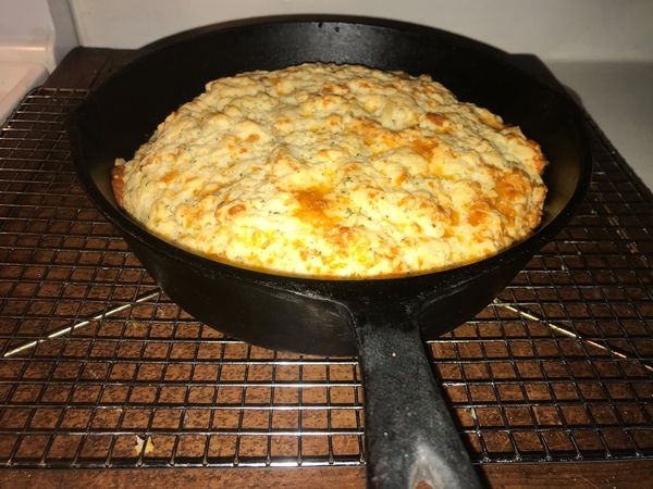 Golden cheesy beer bread just out of the oven in a cast iron skillet – fluffy, easy, and full of cheddar cheese
