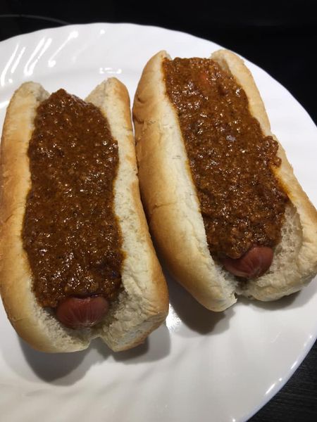 Classic hot dog chili on beef franks, loaded into buns on a white plate – easy homemade hot dog chili recipe