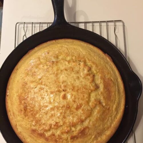 Golden brown traditional Southern cornbread baked in a cast iron skillet, cooling on a wire rack.