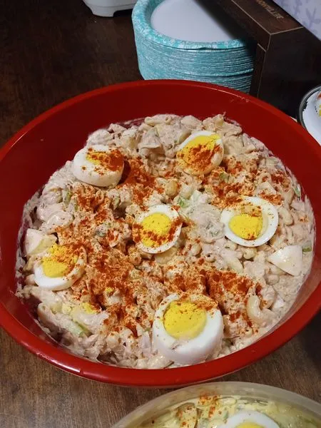 Tuna macaroni salad in a bowl garnished with paprika and egg slices.