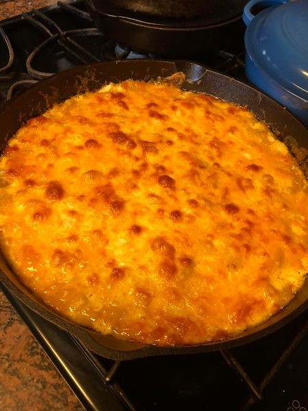 Golden bubbly and browned cheesy crust on Chicken and Cheese Macaroni Bake fresh out of the oven in a cast iron skillet