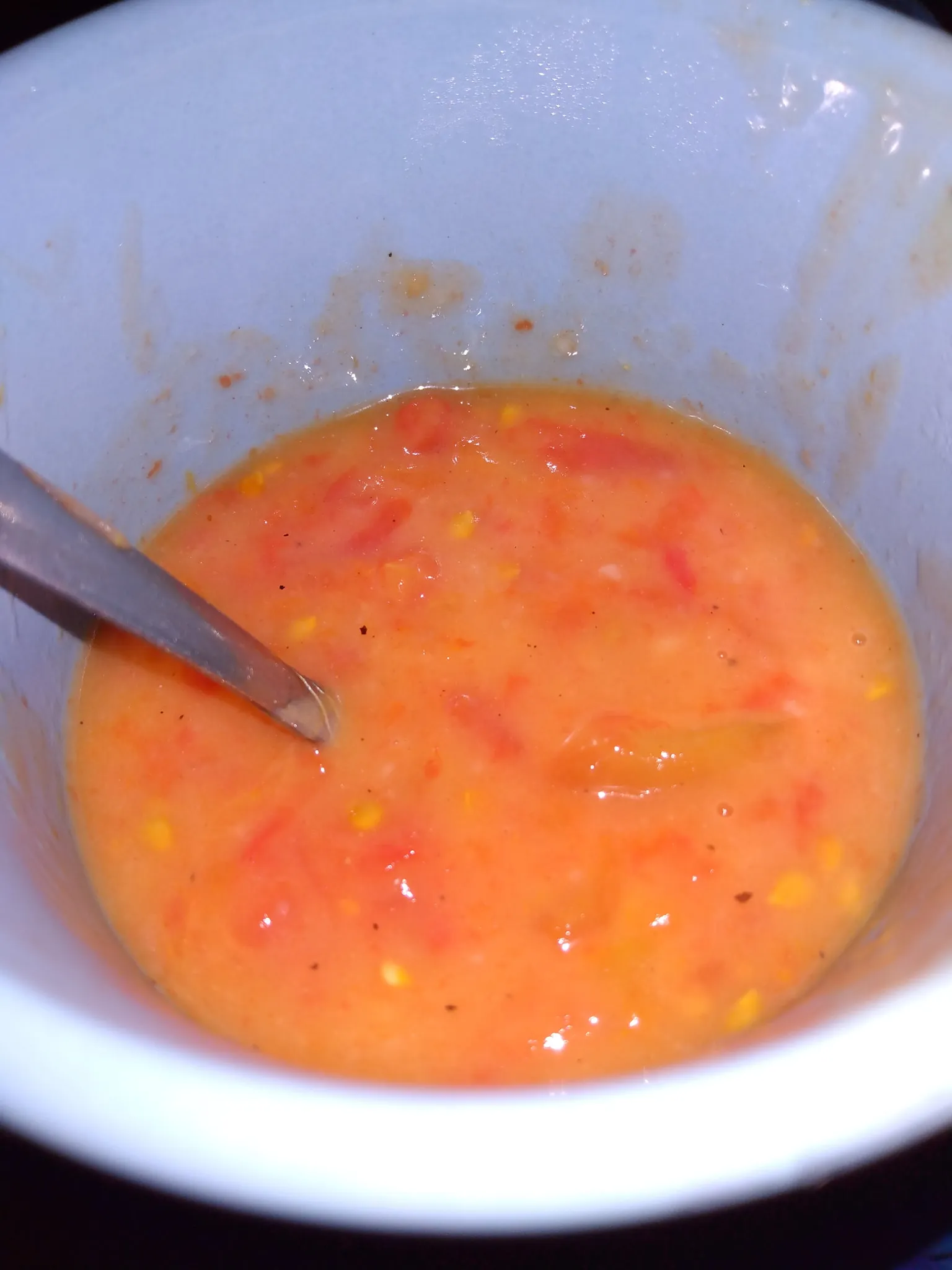 Homemade tomato soup simmering in a saucepan with a wooden spoon