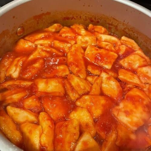 A pot of homemade tomato dumplings bubbling in a rich, savory tomato sauce.