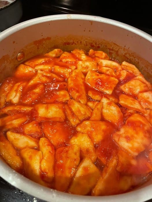 A pot of homemade tomato dumplings bubbling in a rich, savory tomato sauce.