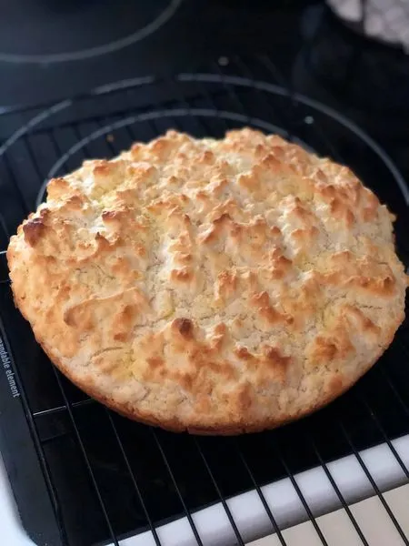 Biscuit bread baked in a cast iron skillet; slice of pone bread with butter.