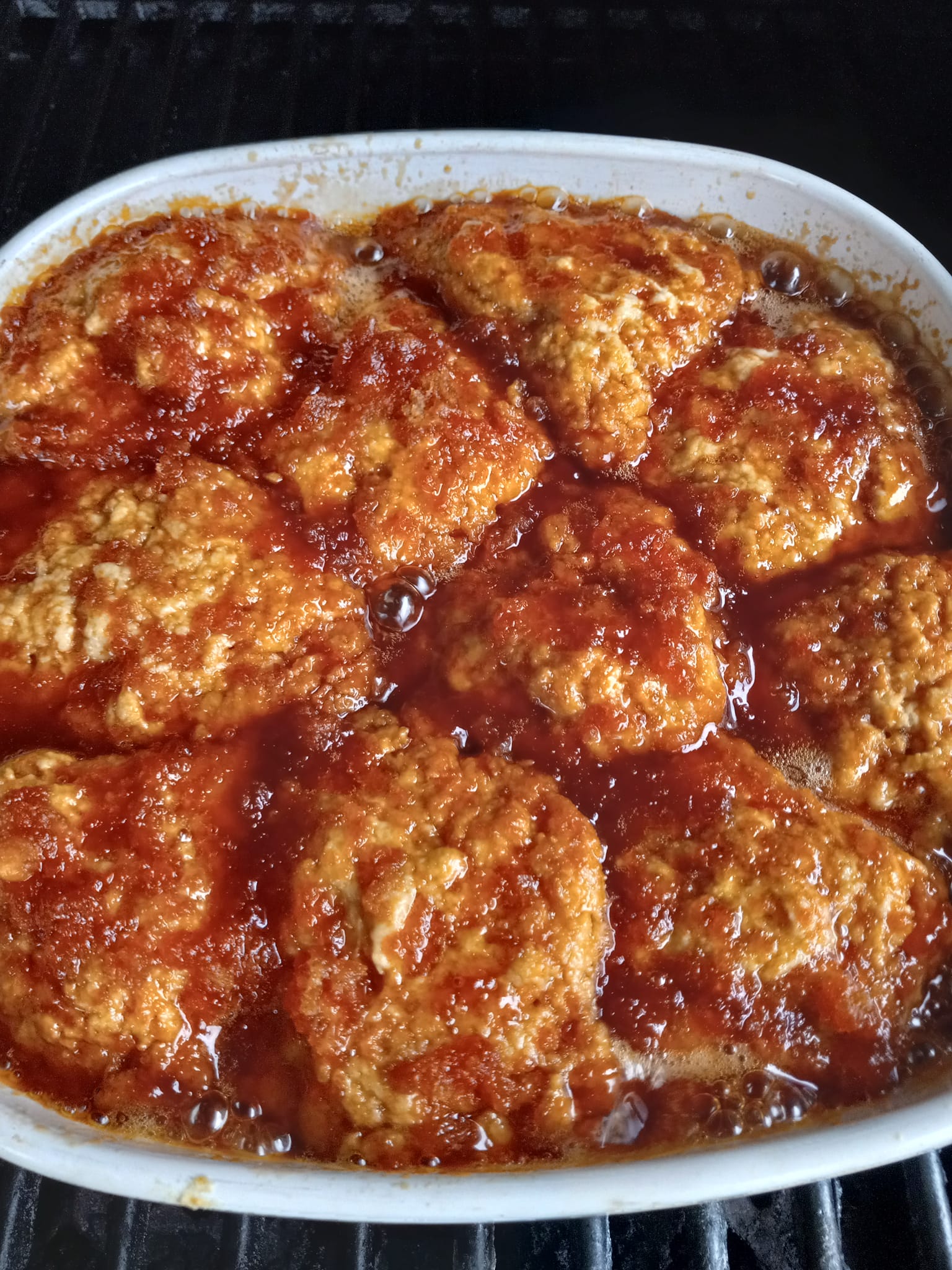 Golden caramel dumplings bubbling in a white baking dish, covered in rich, amber caramel sauce