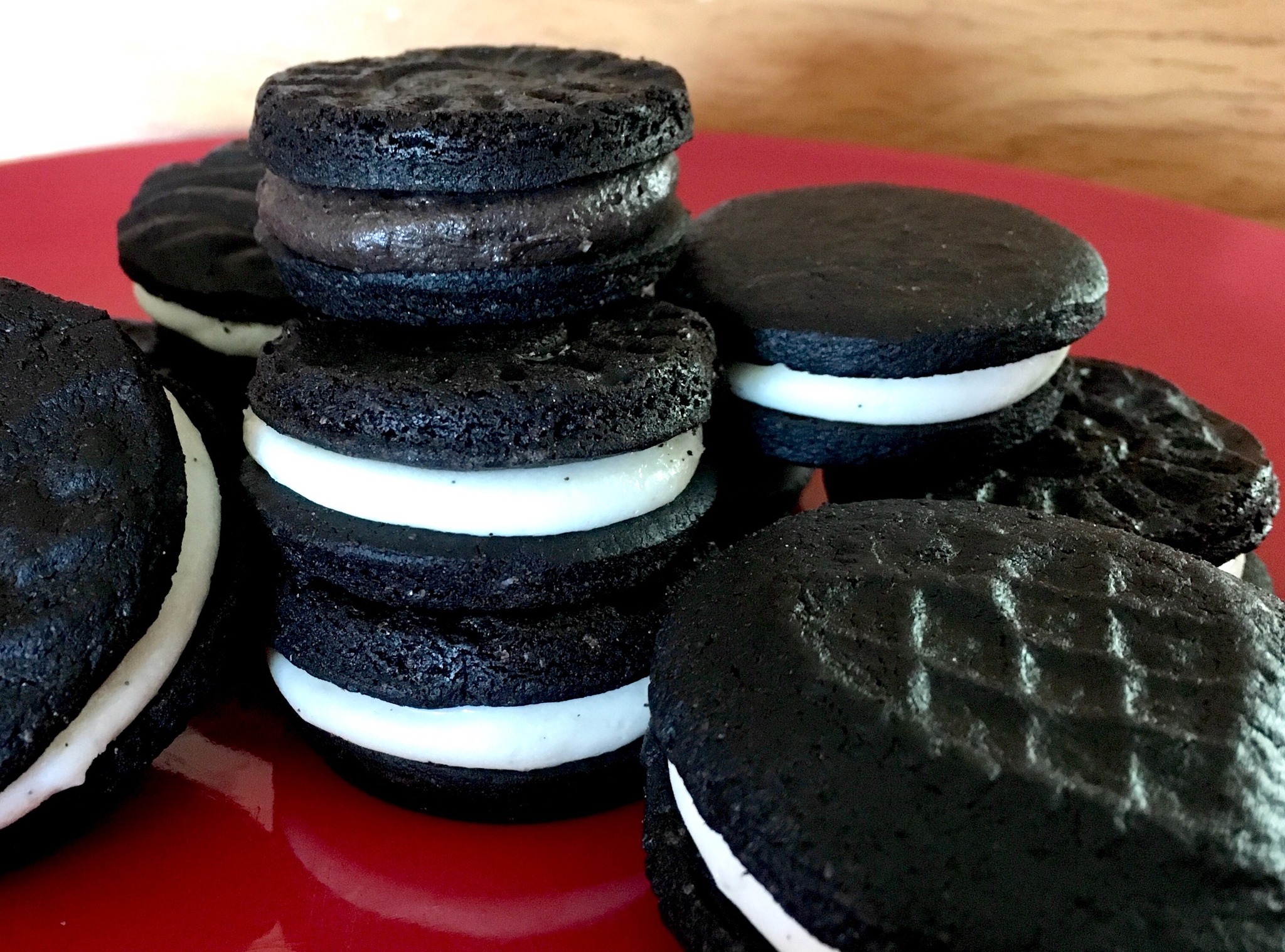 Homemade IleneOs sandwich cookies with cream filling, stacked on a red plate