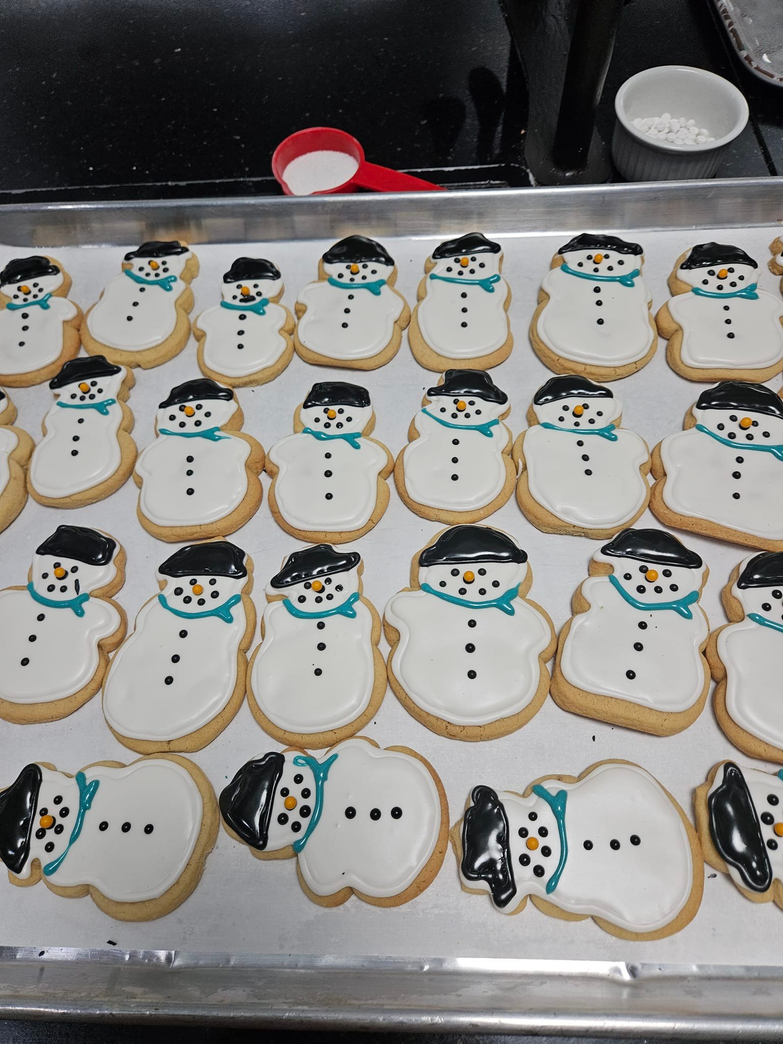 A tray of snowman-shaped sugar cookies decorated with icing for the holidays