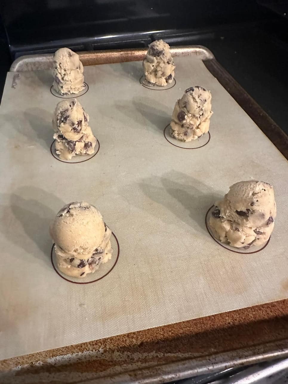 Stacks of chocolate chip cookie dough on a baking sheet ready to be chilled and baked.