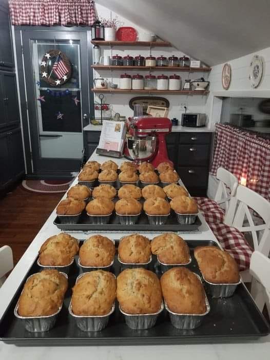 A kitchen table filled with rows of golden Banana Nut Bread loaves fresh out of the oven