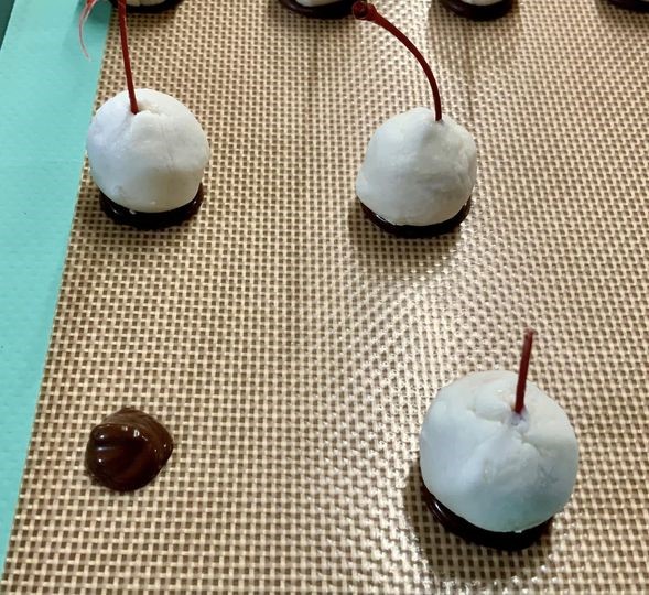 Fondant-wrapped maraschino cherries ready for dipping, on a silicone mat – step-by-step chocolate cherry cordials recipe