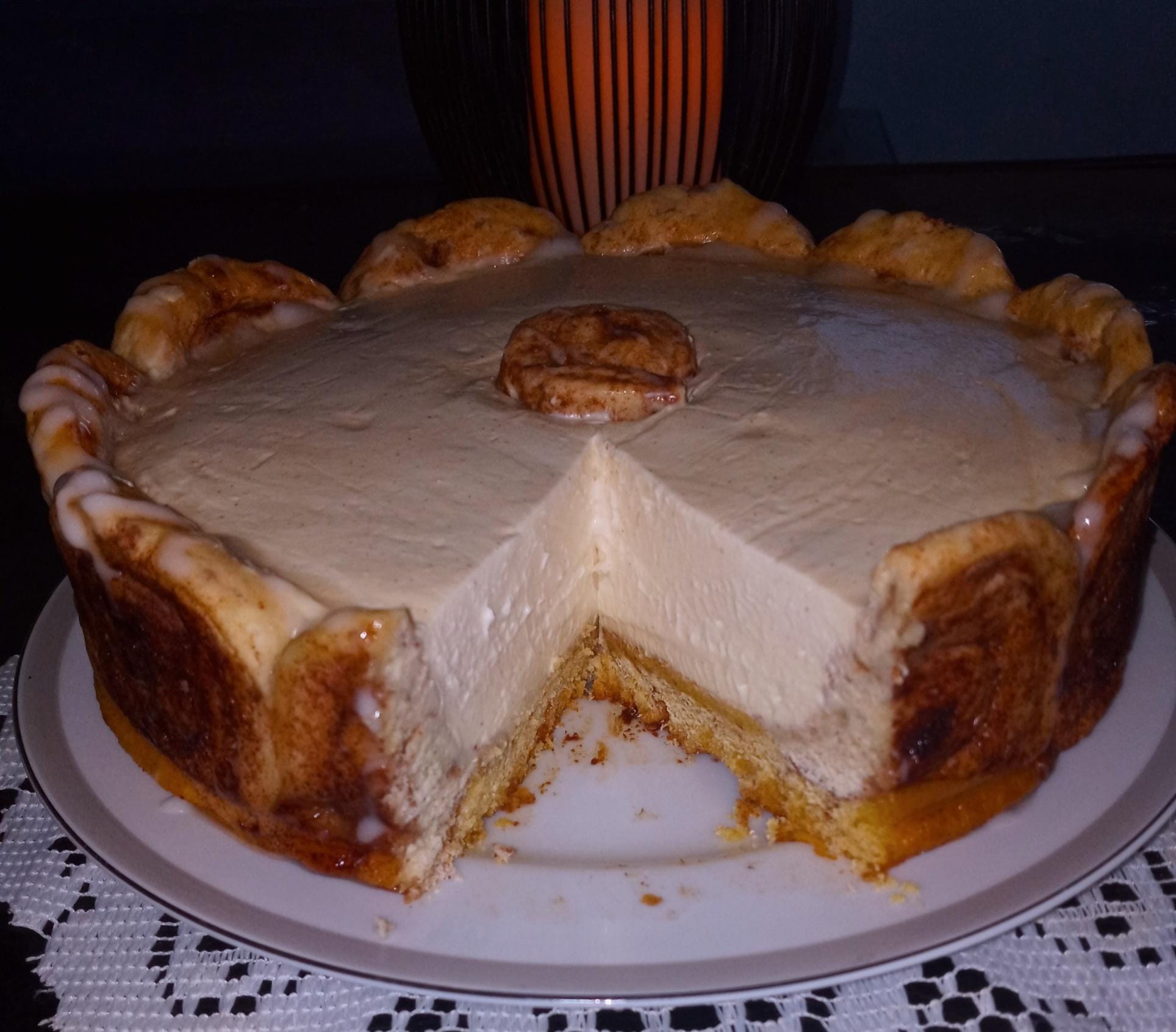 A creamy cinnamon roll cheesecake with a golden crust and icing drizzle