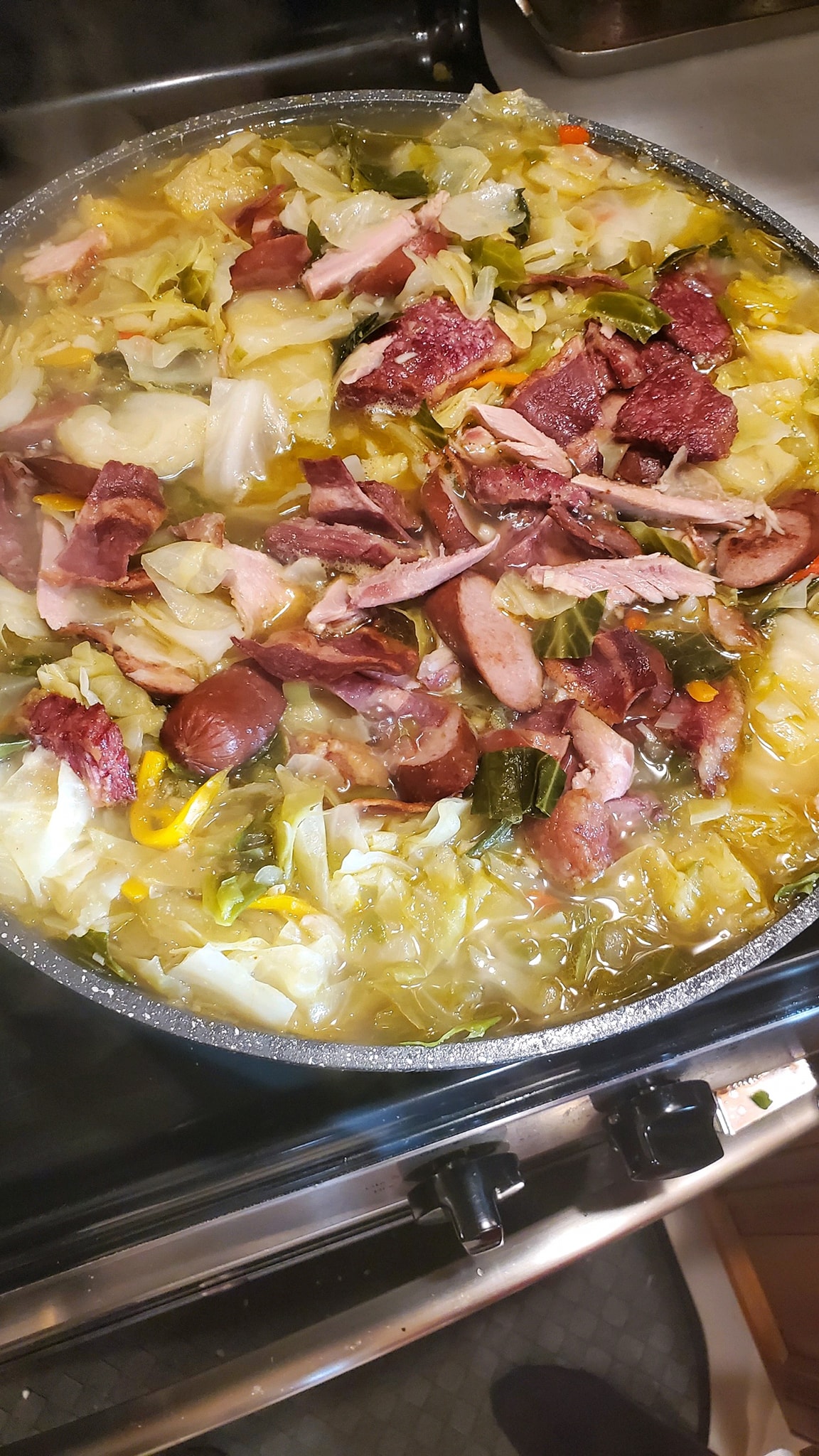 A hearty pot of smothered cabbage with tender cabbage, smoked sausage, turkey, corned beef, and vibrant vegetables simmering to perfection