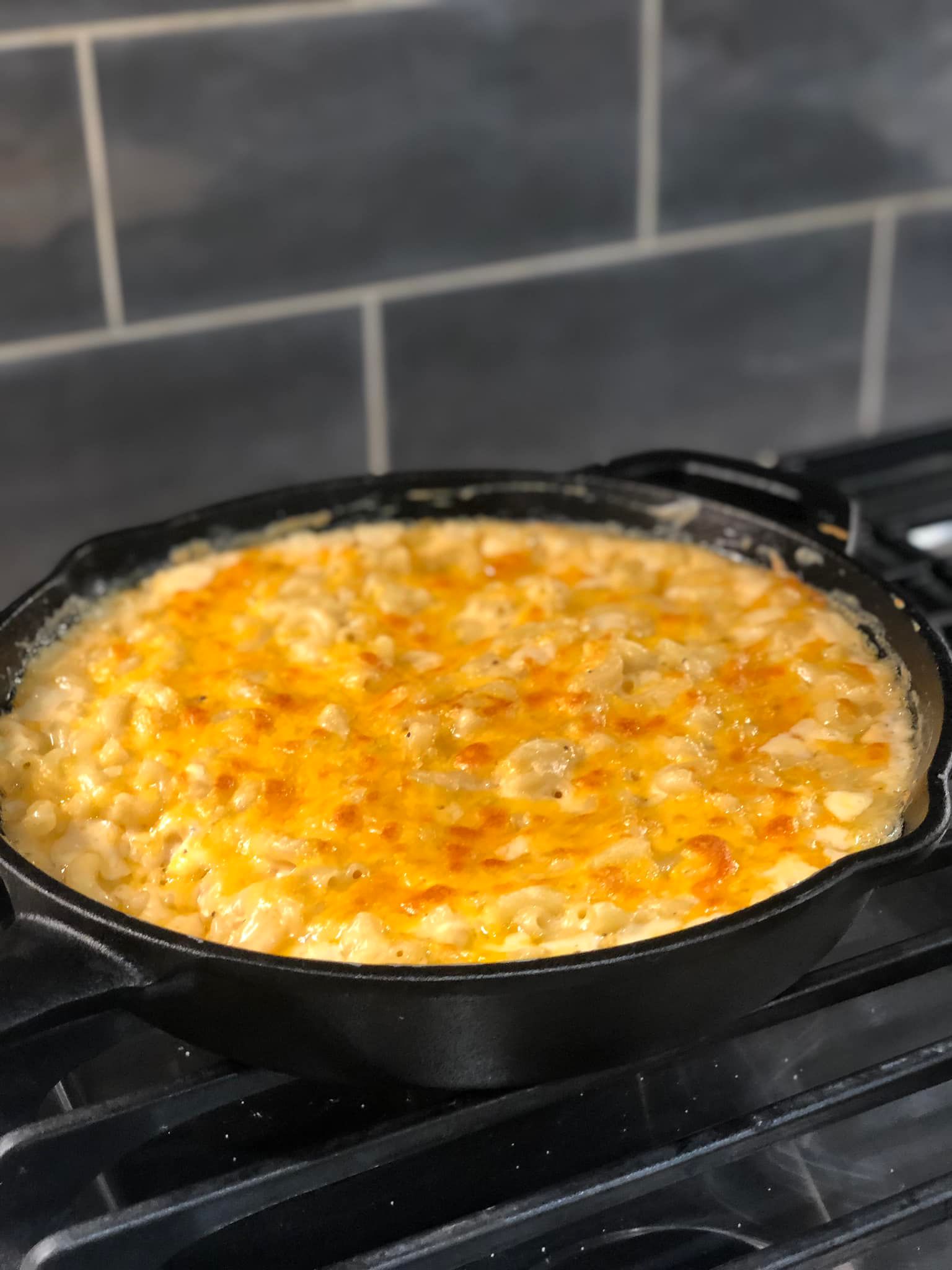 Bubbly baked macaroni and cheese in a cast-iron skillet with a golden, cheesy topping.