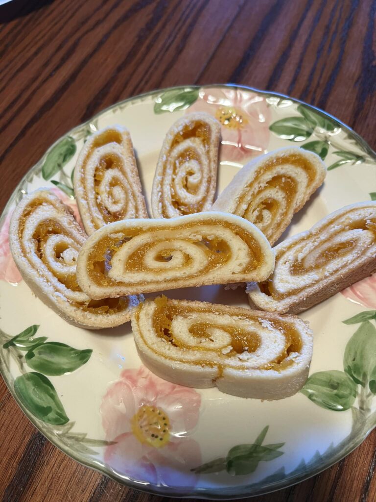 A plate of apricot rolls with golden, swirled apricot filling and buttery dough.