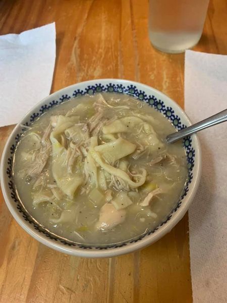 A hearty bowl of chicken noodle soup with shredded chicken, fresh homemade egg noodles, and a clear golden broth