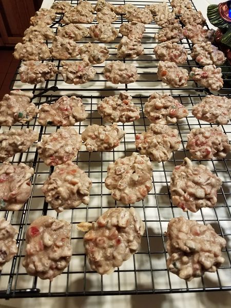 Fruit cake cookies cooling on a wire rack, packed with pecans, cherries, pineapple, and dates."