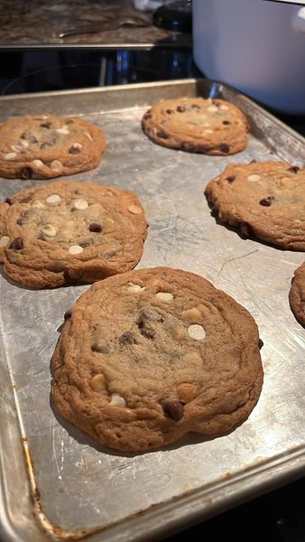 Freshly baked chocolate chip and cream cheese cookies cooling on a rack, golden and packed with chips