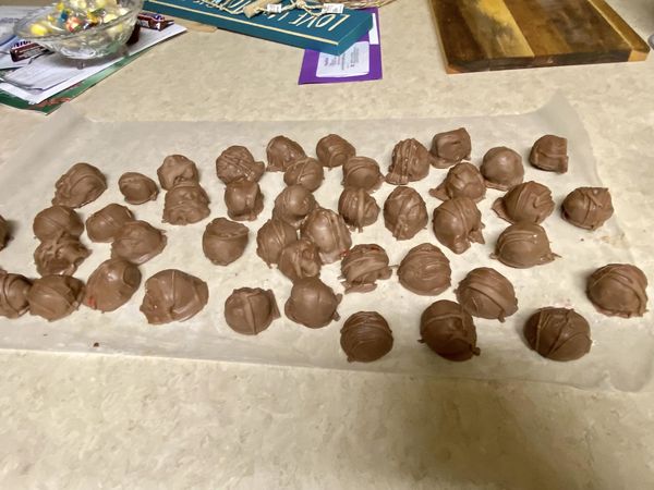 Freshly dipped chocolate covered cherries setting on wax paper