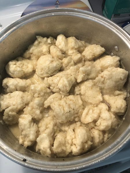 Fluffy dumplings cooking in a pot of savory chicken broth