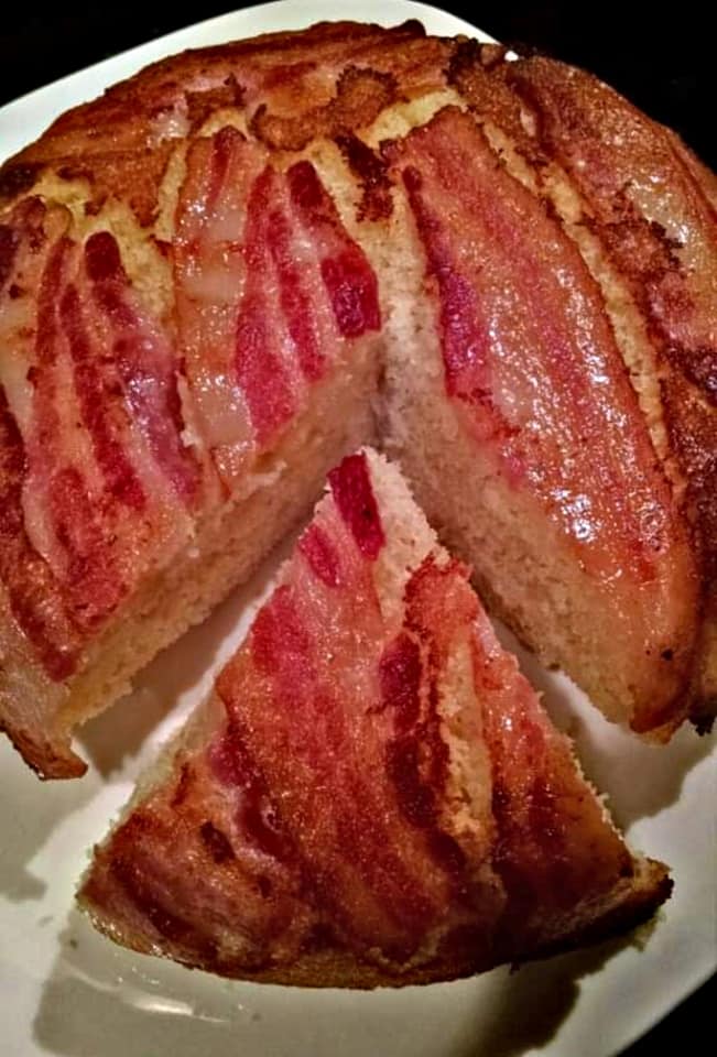 A slice of bacon-topped cornbread with layers of crispy bacon on top of the golden cornbread