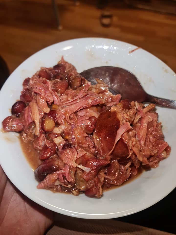 A close-up of creamy red beans, tender hamhock, and sausage in a crock pot