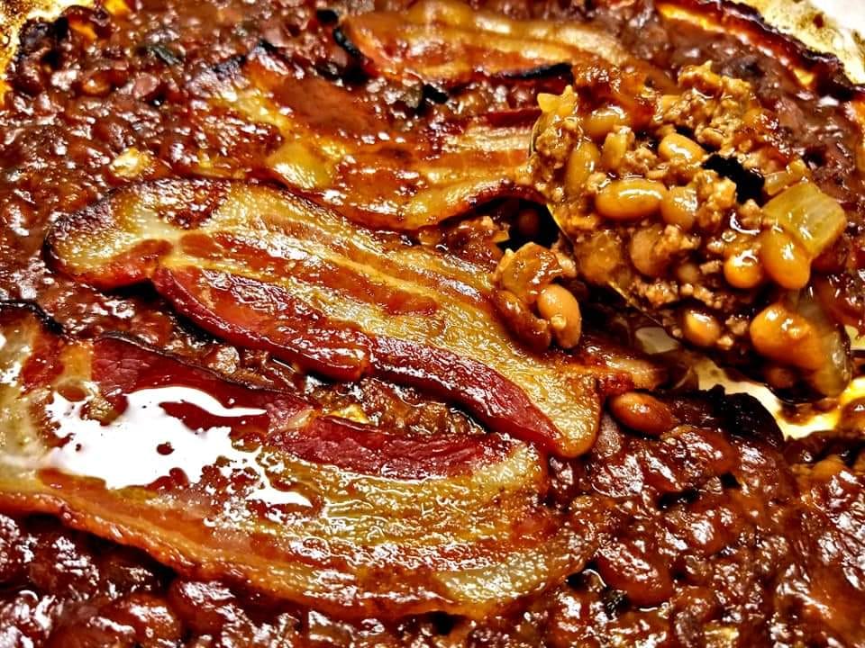 A bowl of cowboy beans fresh from the oven, topped with crispy bacon