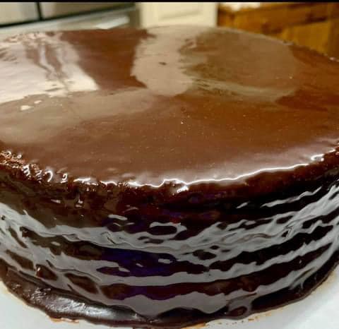 A vanilla layer cake topped with rich, glossy old-fashioned cooked chocolate icing, perfect for any celebration