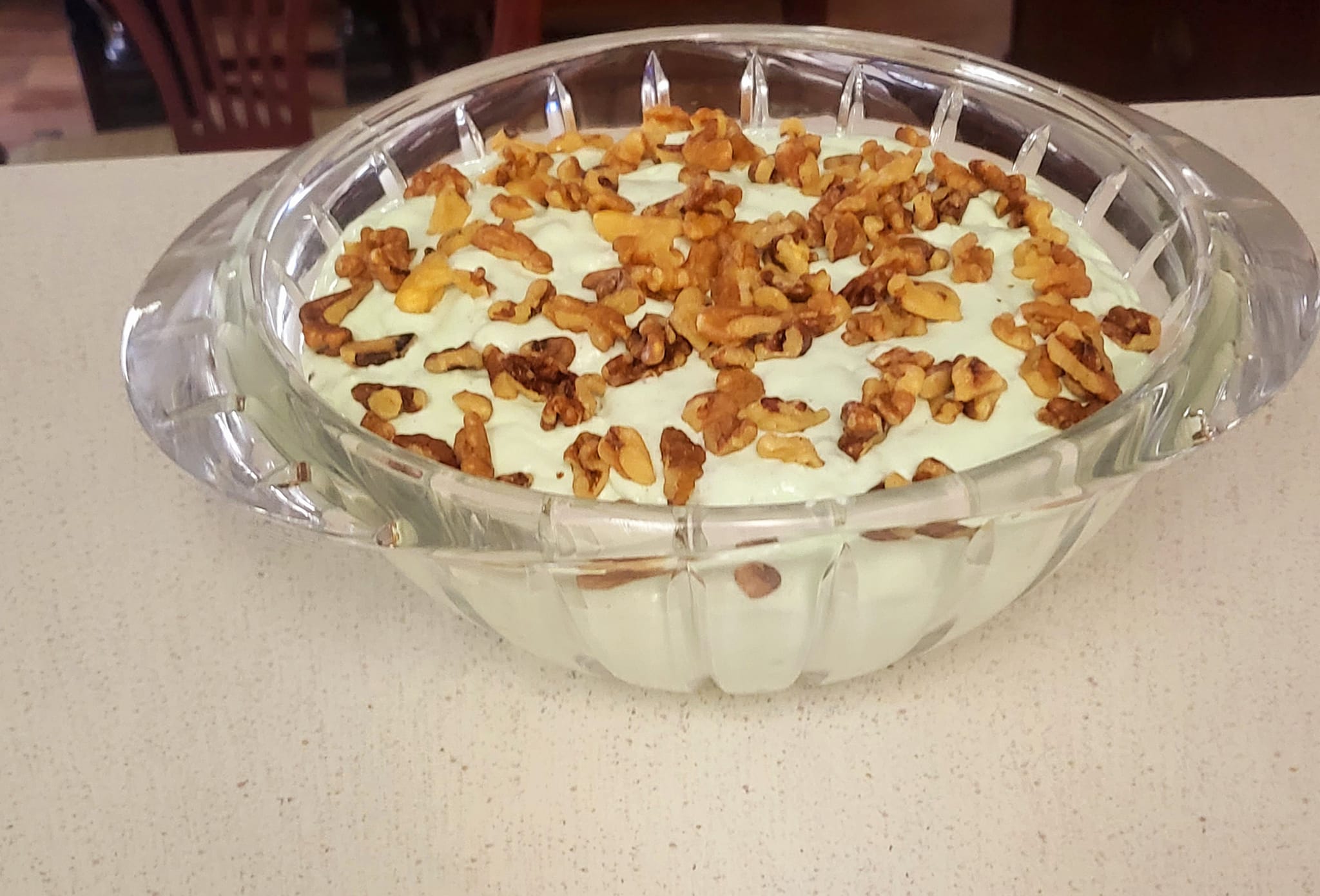 Close-up of lime jello salad topped with walnuts, highlighting the creamy and textured layers