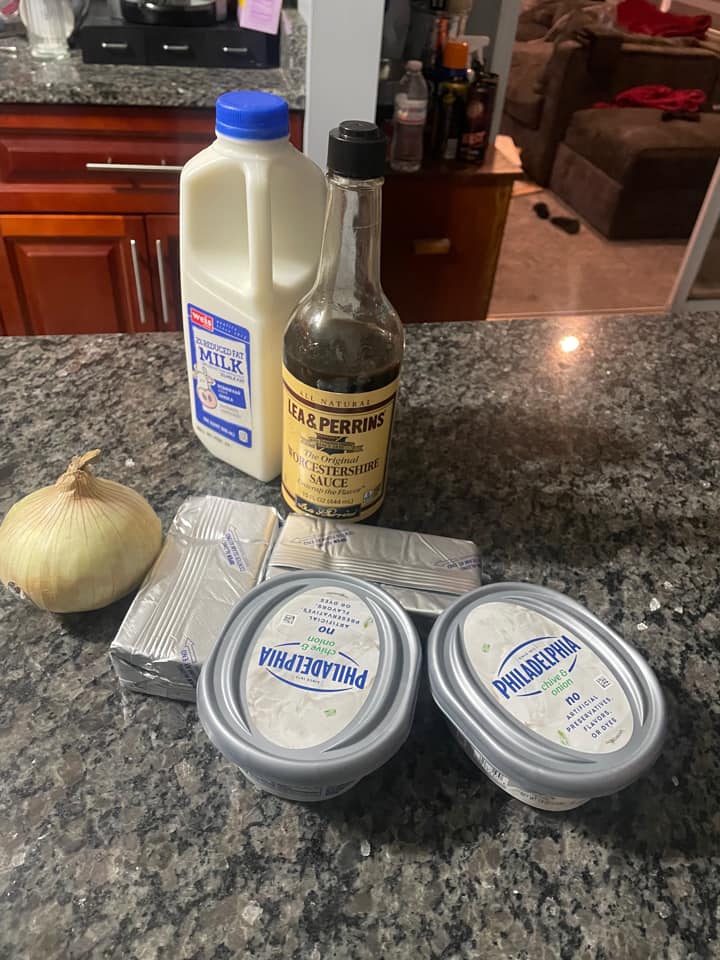 Ingredients for chip 'n dip recipe: Philadelphia cream cheese, chive cream cheese, milk, Worcestershire sauce, and onion on a kitchen counter