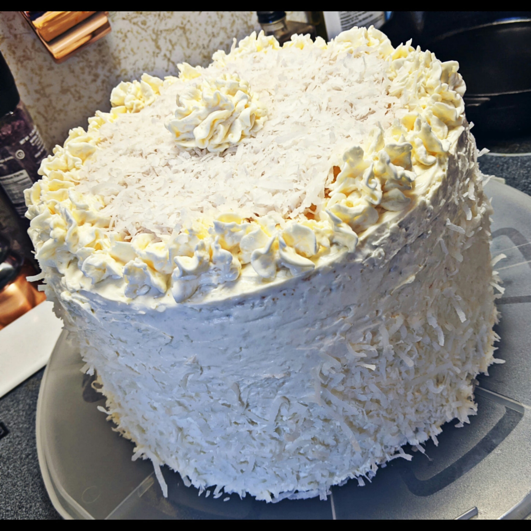 Side view of a vanilla coconut cake with cream cheese frosting and coconut flakes, perfect for celebrations