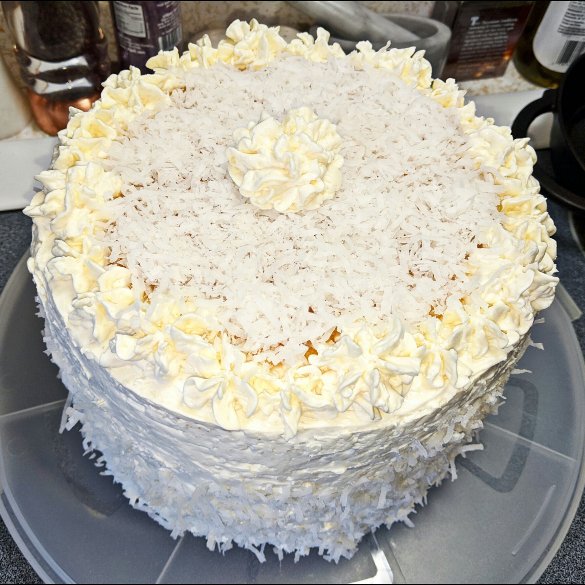 A beautifully frosted vanilla coconut cake with cream cheese coconut frosting and shredded coconut topping