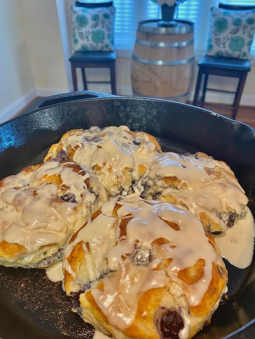 Golden-brown lemon blueberry glazed biscuits in a cast-iron skillet