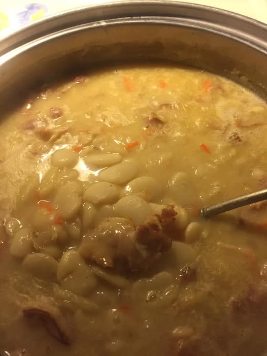 A pot of creamy lima beans with bacon, carrots, and a rich broth, ready to serve.