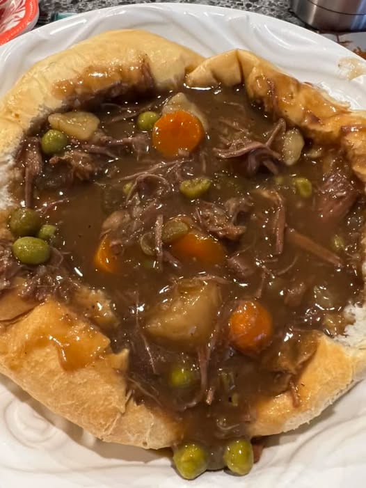 Rich and hearty homemade beef stew with vegetables served in a golden-brown bread bowl.