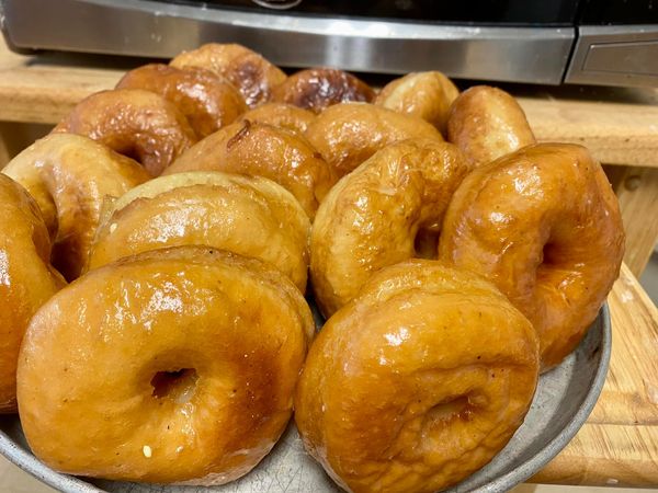 Freshly fried homemade donuts, golden-brown and glistening with glaze.