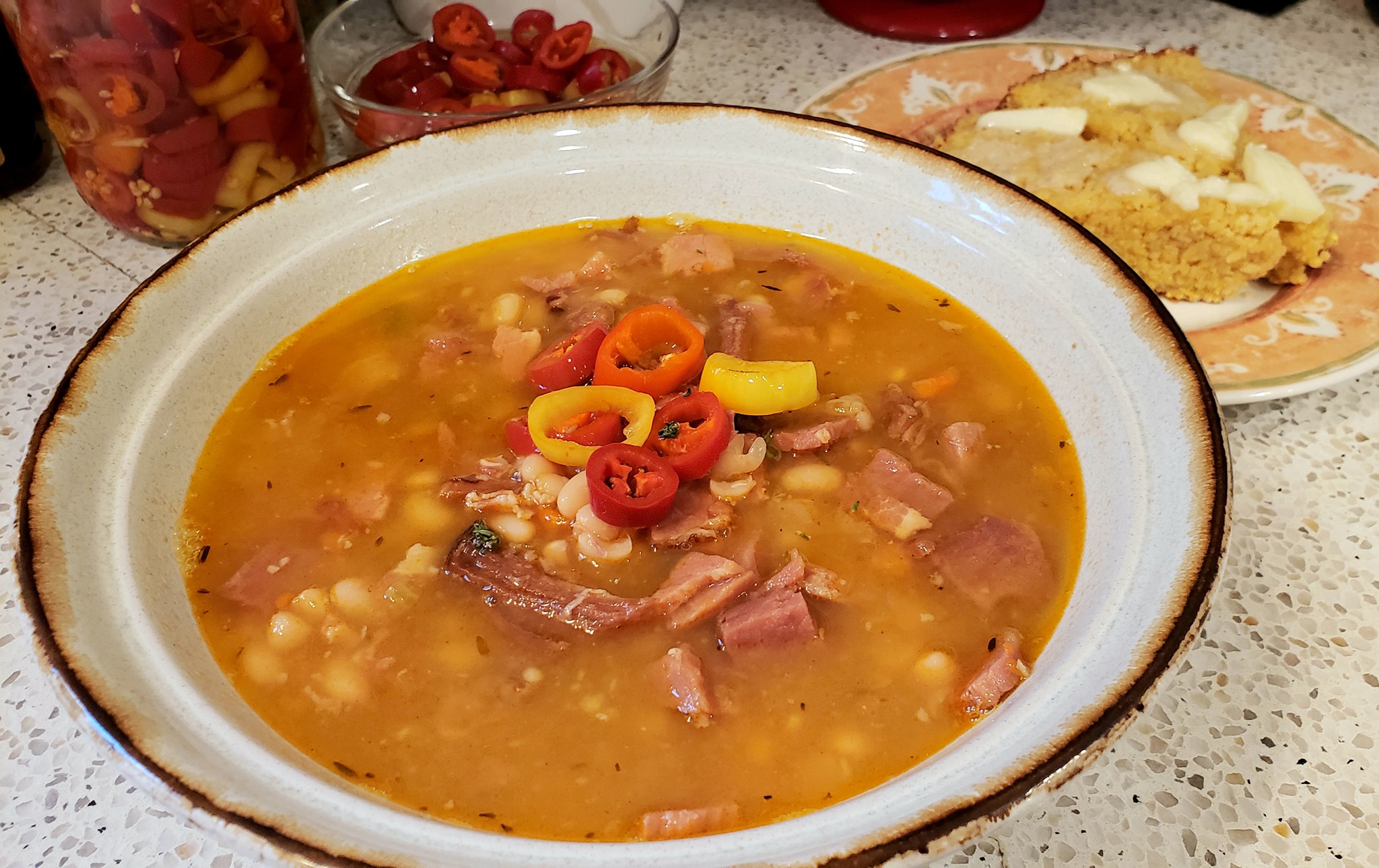 Bright red pickled peppers and vinegar drizzled over navy bean soup.