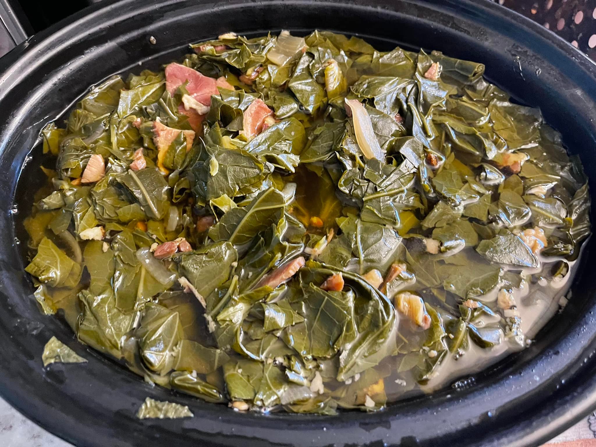 Slow-cooked Mississippi collard greens in a crockpot with peppers and onions, served in a bowl with golden cornbread