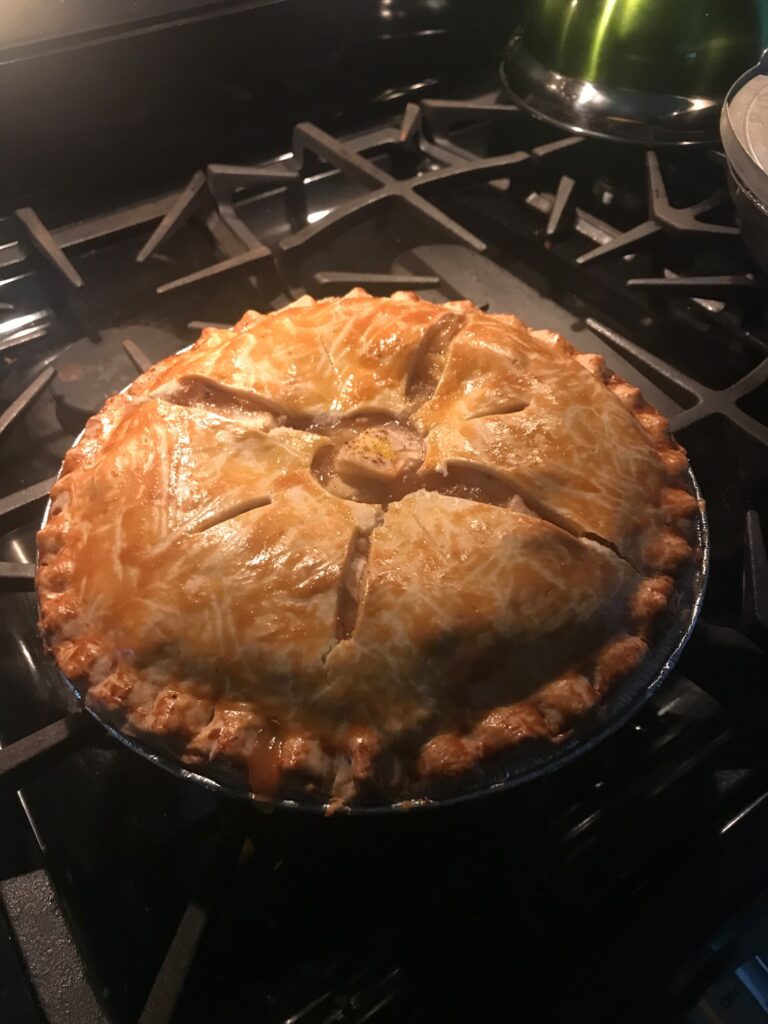 Golden double-crust apple pie with cinnamon-spiced apples on a vintage ceramic plate, garnished with fresh thyme