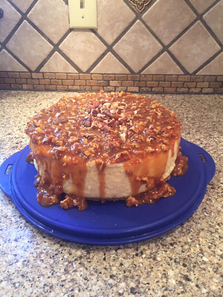 Homemade cheesecake with salted caramel pecan topping, drizzling down the sides