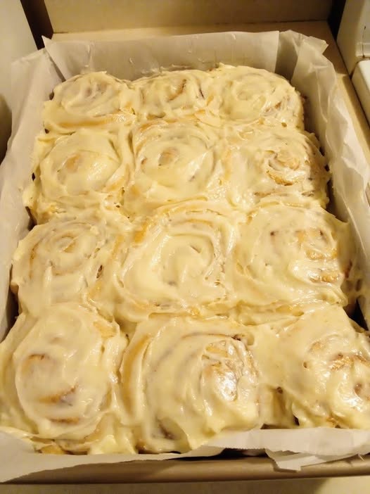Freshly baked cinnamon rolls with golden tops, ready for frosting.