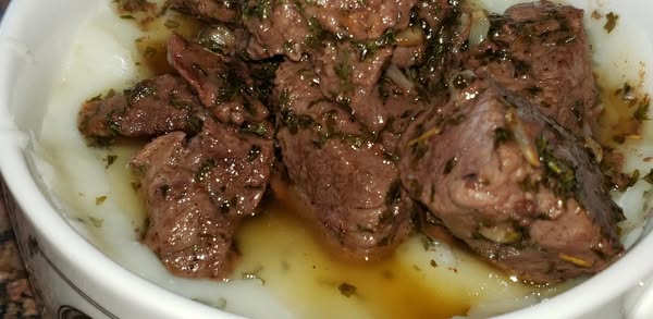Garlic butter steak bites served over creamy mashed potatoes, drizzled with garlic butter sauce