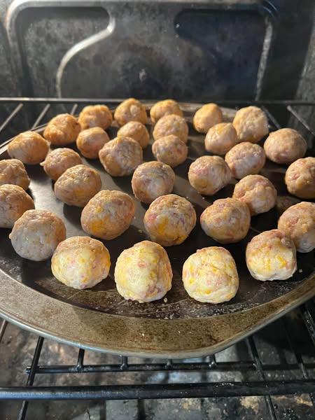 Sausage balls baking in the oven, showing the transition from raw to golden brown for a delicious appetizer