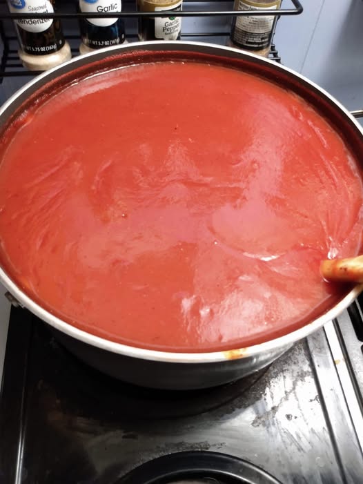 A pot of homemade no-sugar ketchup simmering on the stove, rich in color and texture.