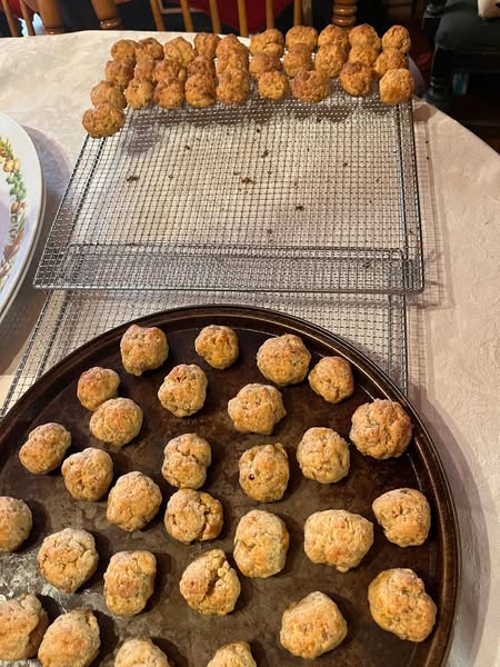Cooked sausage balls cooling on a wire rack and baking sheet, showcasing a large batch of the easy appetizer