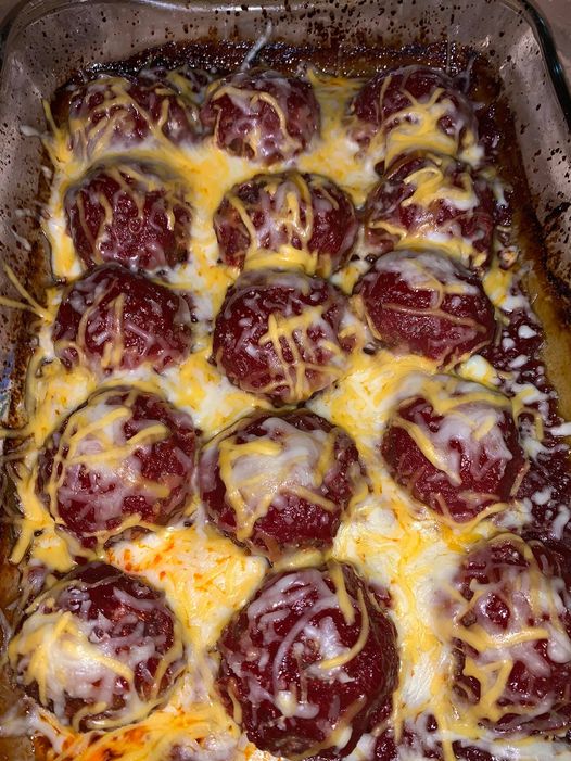 A pan of homemade deer meatballs topped with melted cheese, baked in a rich tomato sauce.