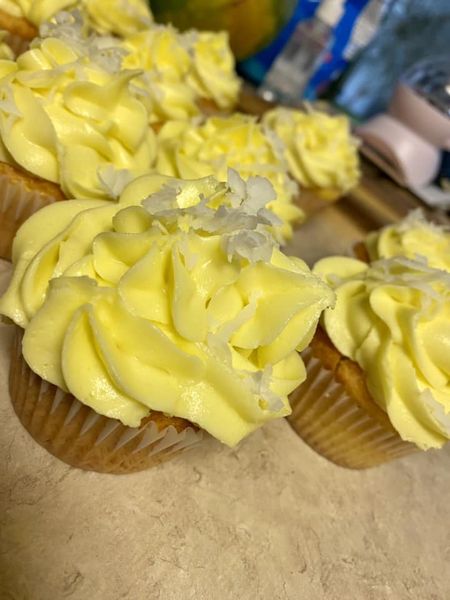  detailed view of a Pina Colada cupcake with smooth pineapple-flavored frosting and coconut flakes, perfect for a tropical dessert